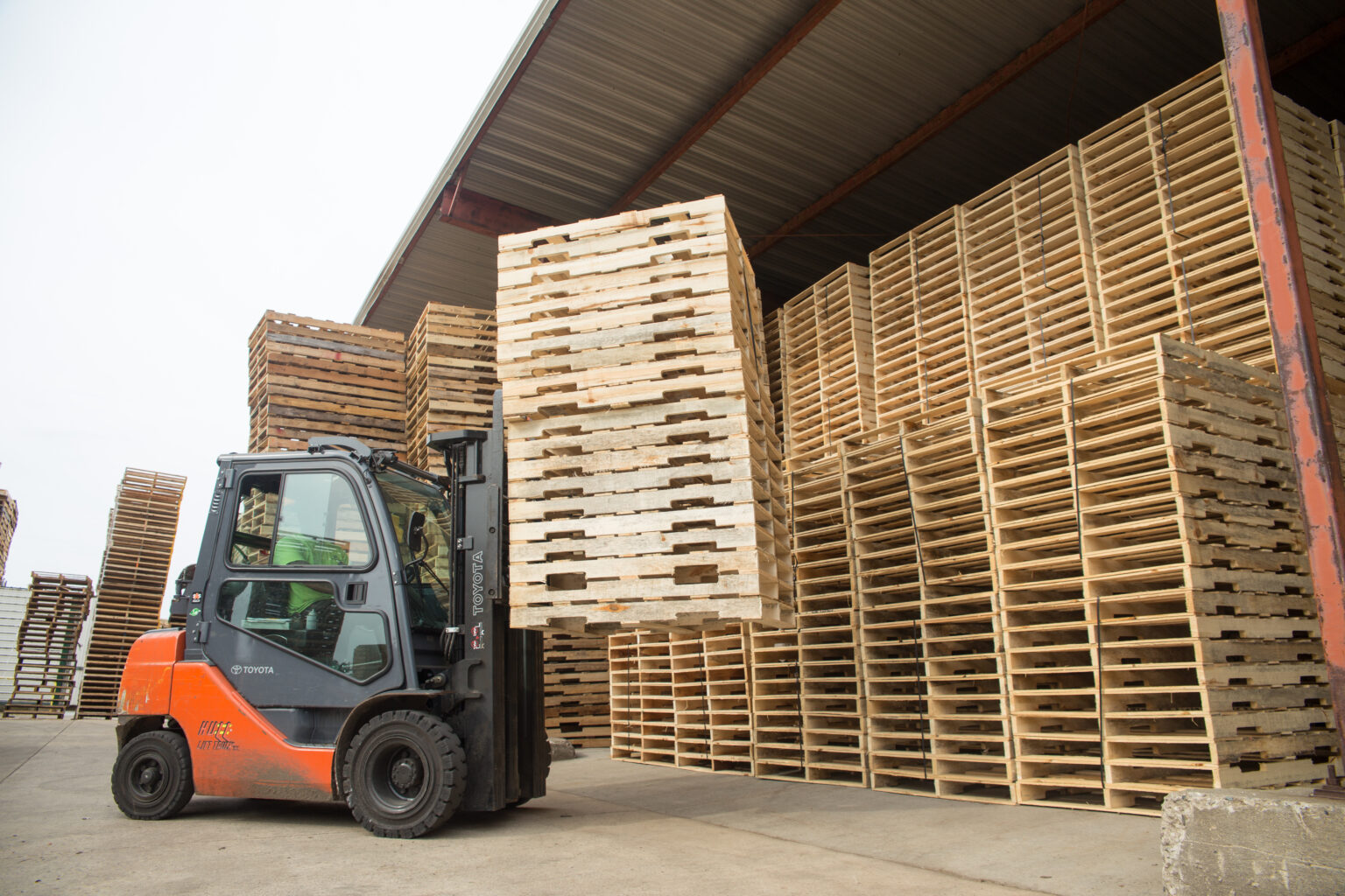 A hi-lo picking up a stack of custom-made new pallets